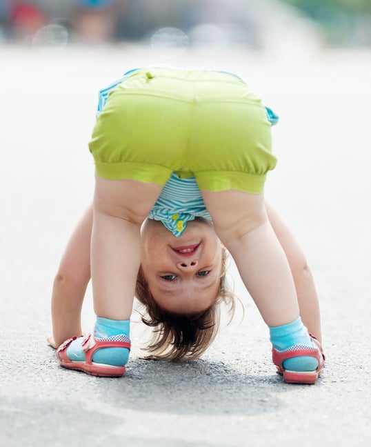 three-year baby girl playing upside down