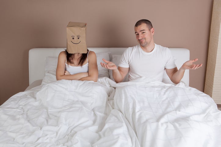 Funny situation in bed. Woman with paper bag over head