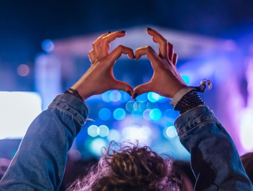 woman holding up heart hands during concert