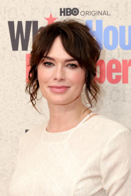 Lena Headey attends HBO's "White House Plumbers" wearing her brown hair up with some pieces falling down wearing a long sleeved white top.