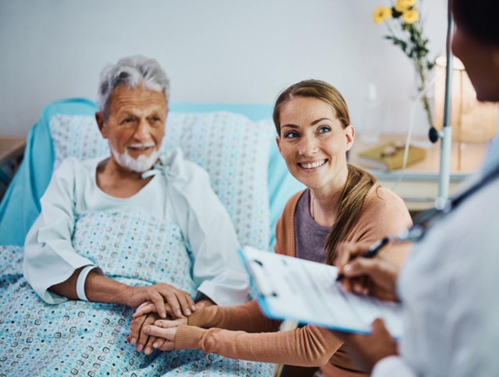 Woman sitting with an elderly man in the hospital.