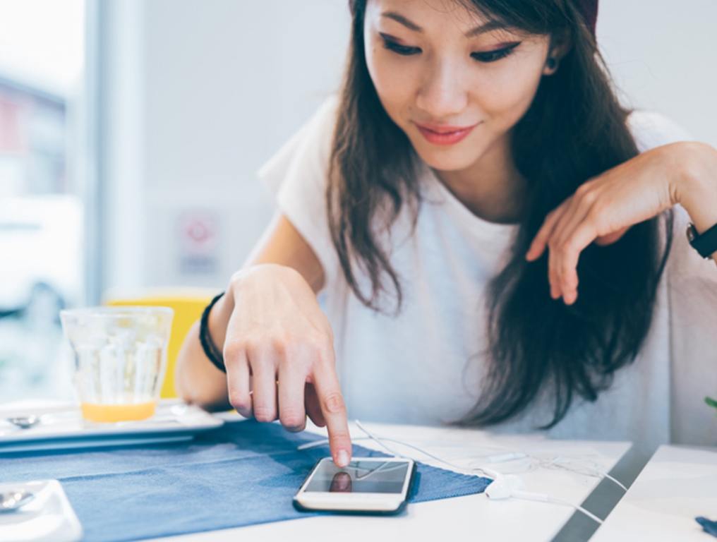 woman sitting in a bar, using a smart phone tapping the touchscreen - technology, social network, communication, tik-tok tests concept.