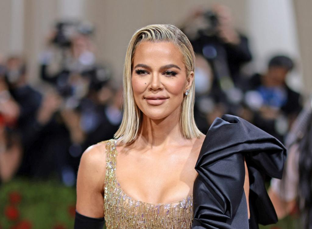 Khloé Kardashian attends The 2022 Met Gala Celebrating "In America: An Anthology of Fashion" smiling facing left wearing a gold gown with black gloves.