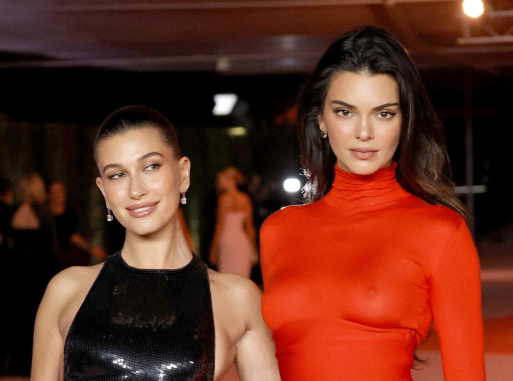 Hailey Bieber wearing a black dress looking right and Kendall Jenner wearing a red dress attend the 3rd Annual Academy Museum Gala.