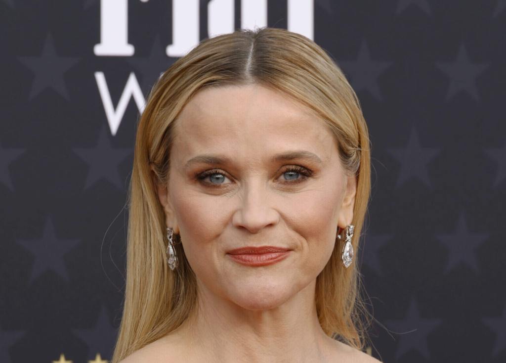 Reese Witherspoon attends the 29th Annual Critics Choice Awards smiling wearing dangly earrings.