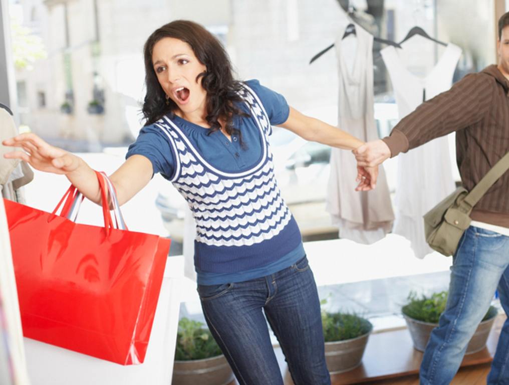 Man in store trying to pull woman away from clothes rack, chaos, frenzy, shopping concept.