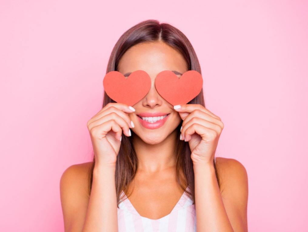 Close up portrait of cute sweet pretty beautiful lovely gorgeous hold two small little thematic red shape cards close eyes she isolated on vivid pink pastel background in her white casual wear, Valentine's or Galentine's concept.