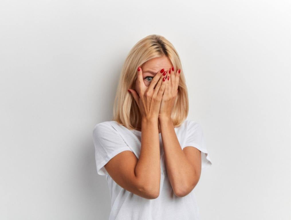 shy girl hiding behind her palms, close up portrait, isolated white background, studio shot, copy space