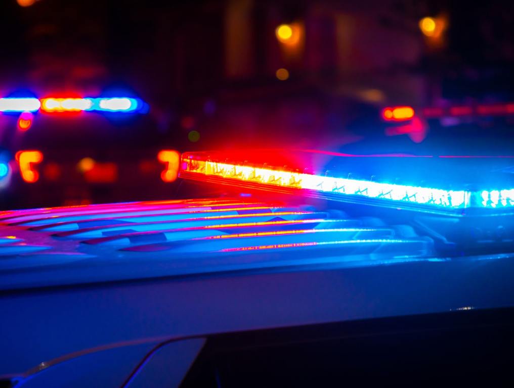 Red and blue police lights near a car crash in a city at night.