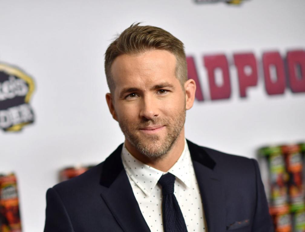 Deadpool actor standing in front of step and repeat.