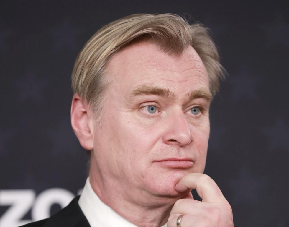 Christopher Nolan, winner of the Best Picture Award for 'Oppenheimer,' poses in the press room during the 29th Annual Critics Choice Awards at Barker Hangar on January 14, 2024 in Santa Monica, California. he has his finger up to his chin.