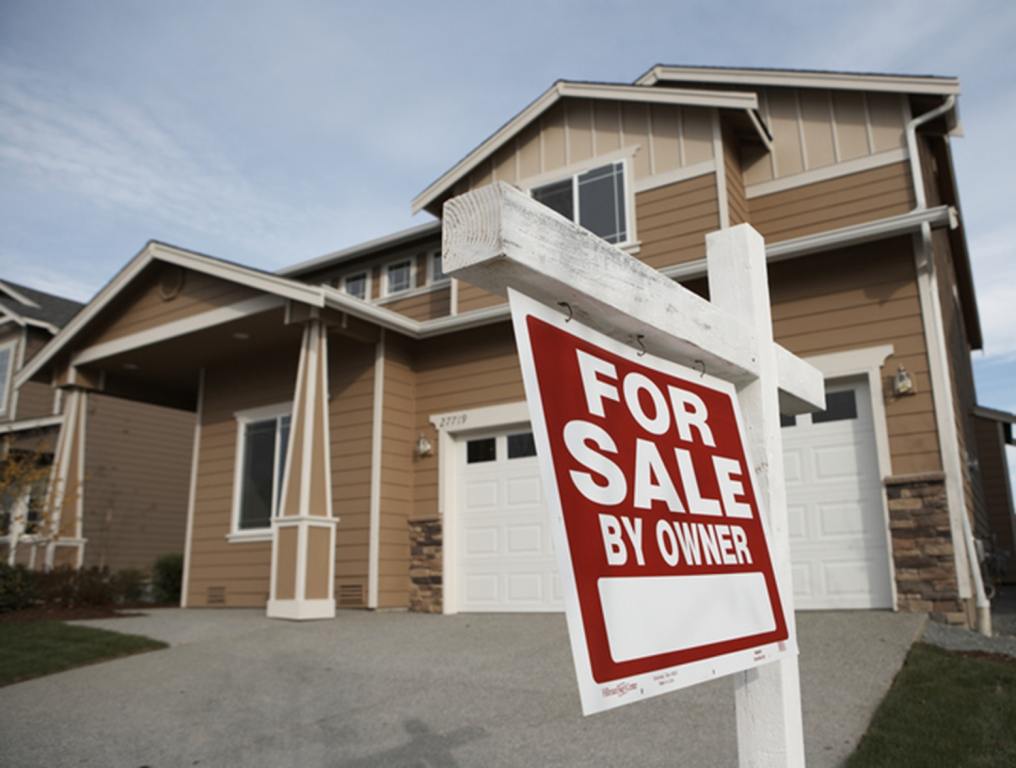 'For Sale' sign in front of house (focus on sign)