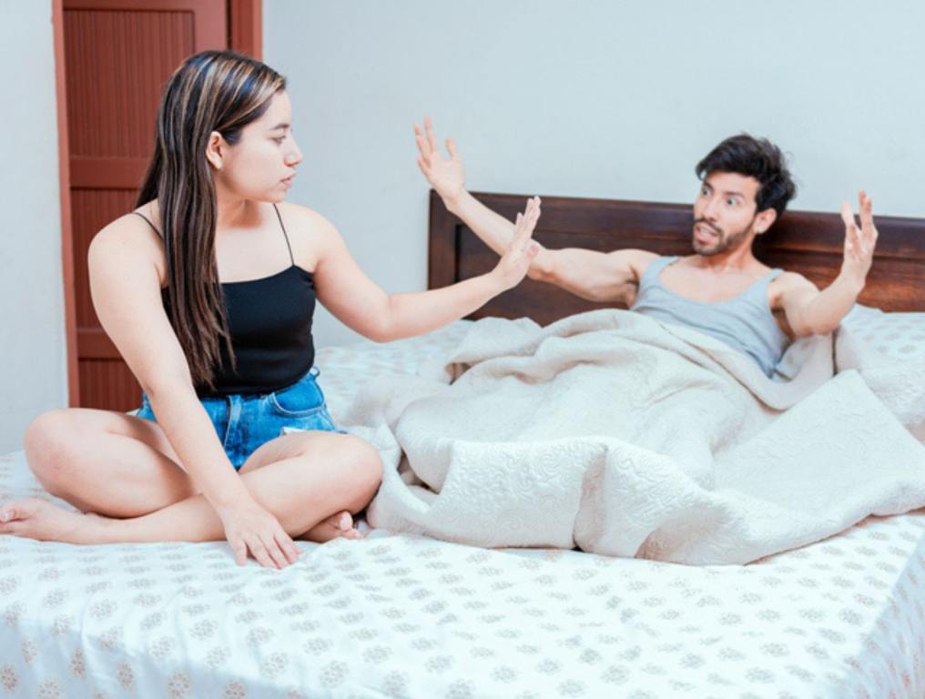 Upset woman with husband in bedroom bed, Husband fighting with his wife in bed. Young couple arguing in bed room. Concept of couple problems in bed