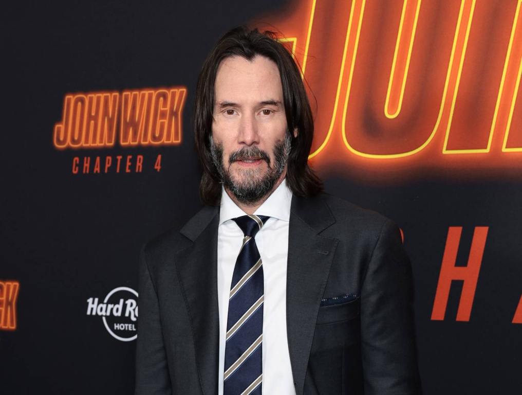 keanu reeves posing in front of john wick step and repeat sign