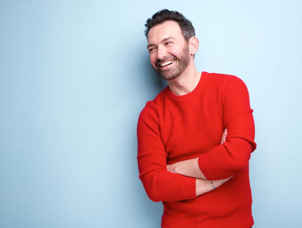 A man smiling in a red shirt.