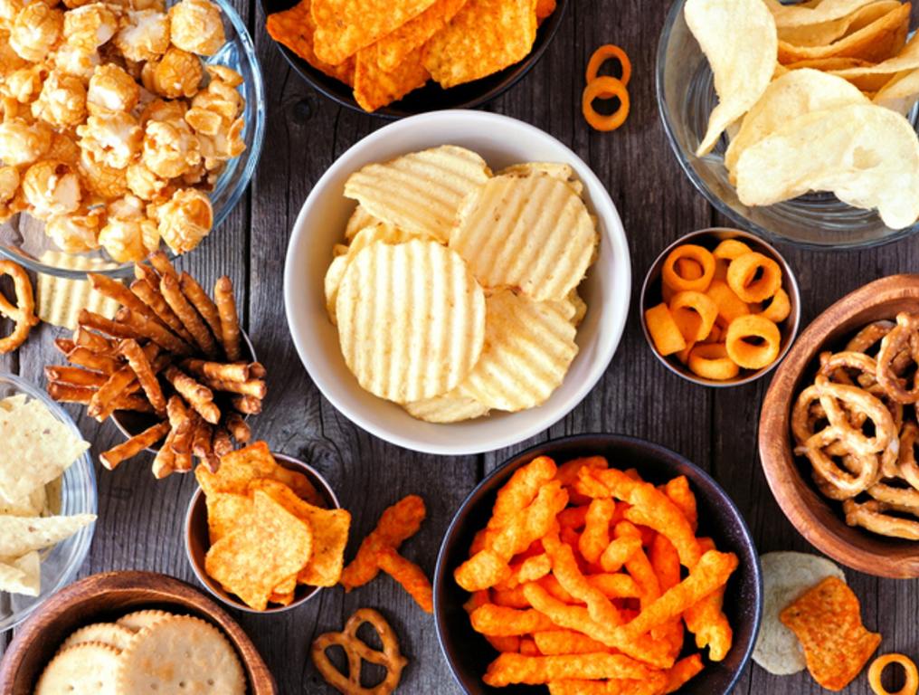 Mixed salty snacks. Flat lay table scene on a rustic wood background.