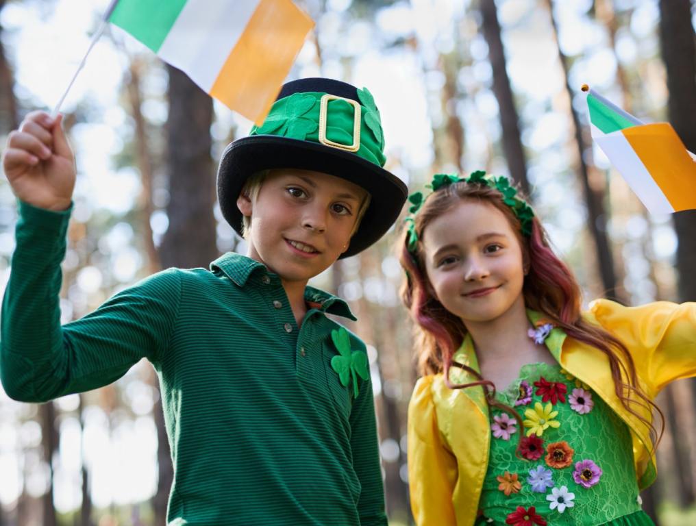 Happy kids celebrating St Patrick's Day on the 17th of March. Portrait of cheerful white children dressed in green festival costumes and waving with Irish flags. St. Patrick's Day family events in Las Vegas.