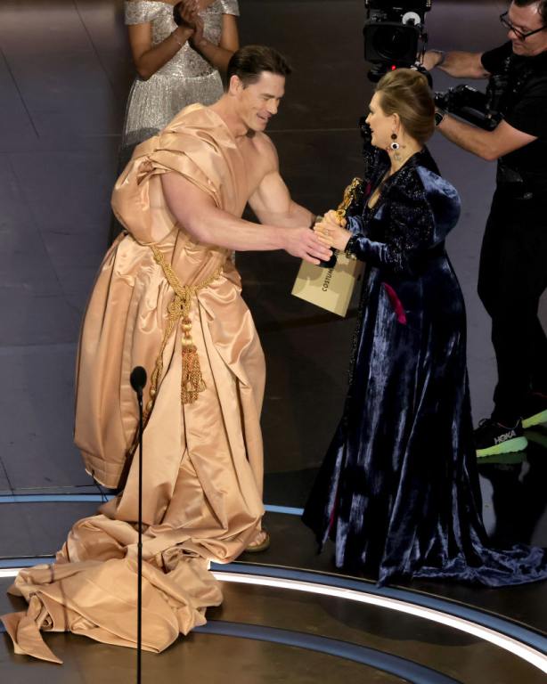 (L-R) John Cena presents the Best Costume Design award for "Poor Things" to Holly Waddington onstage during the 96th Annual Academy Awards at Dolby Theatre on March 10, 2024 in Hollywood, California.