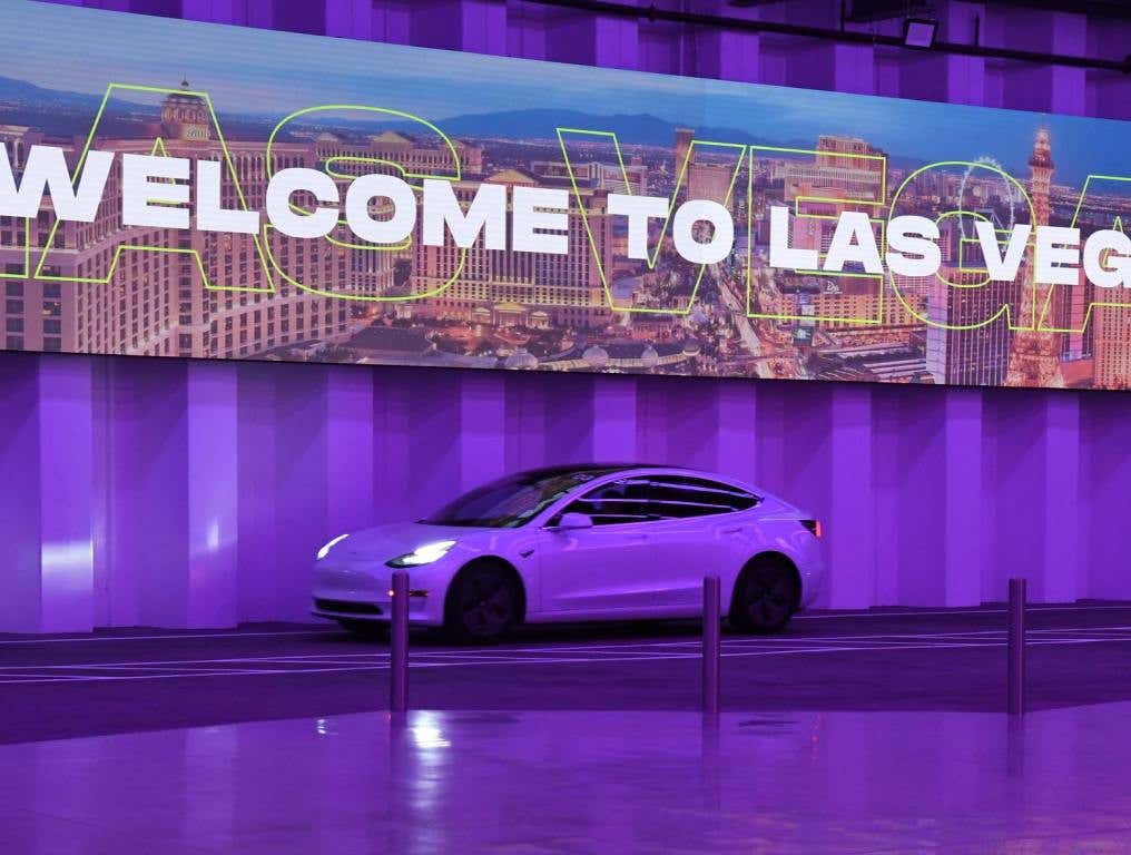 tesla traveling in tunnel beneath digital screen in purple light