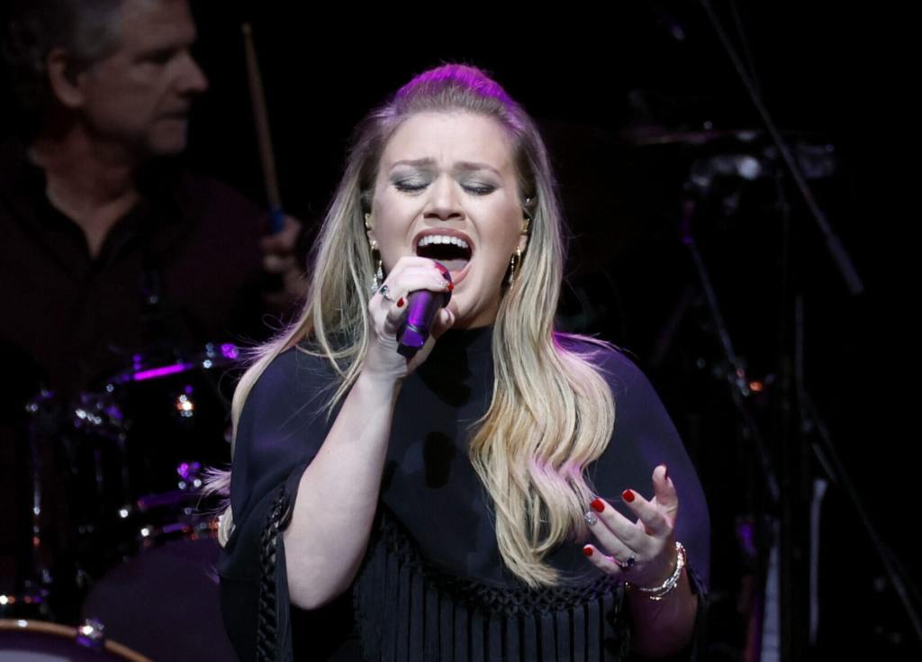 Kelly Clarkson performs onstage for The Final Nashville Show - A Tribute To Ronnie Milsap wearing a black shirt singing holding a microphone with her eyes closed, Kelly Clarkson's Best Kellyoke Performances Of 2024 (So Far).