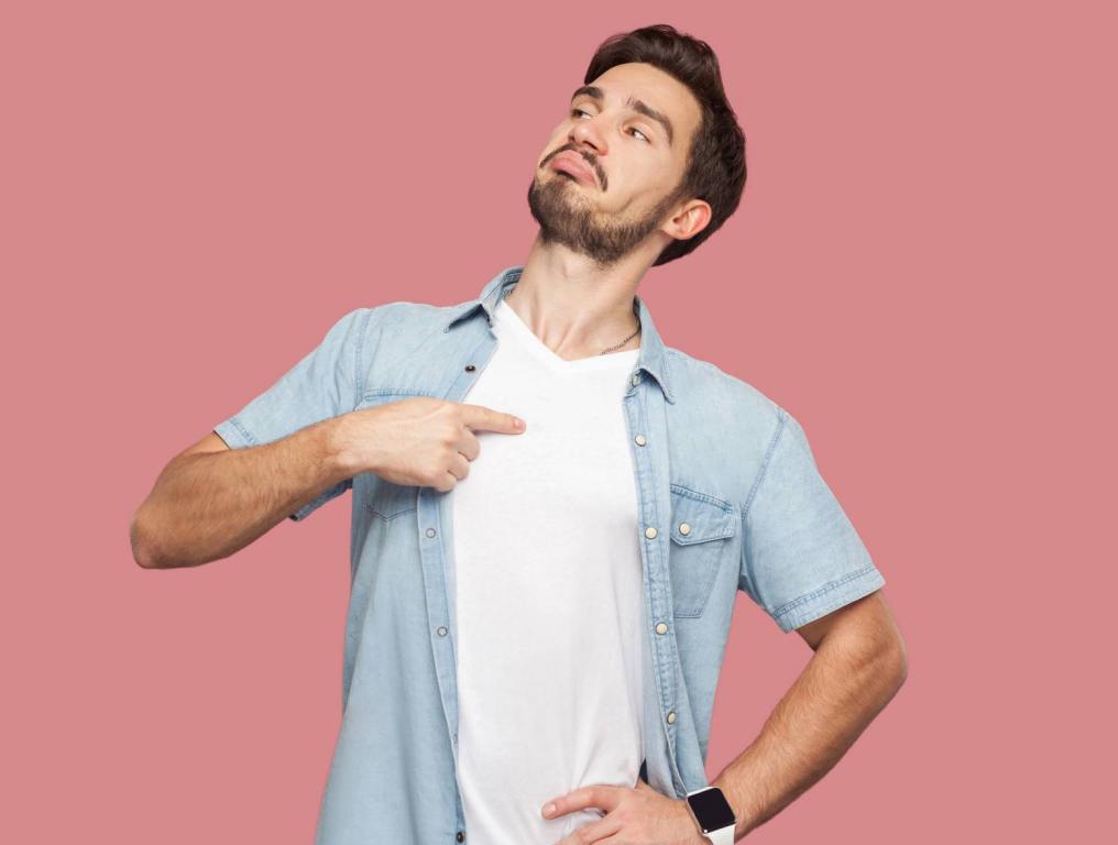 man pointing at himself with head pointed up in front of pink background illustrating how to deal with narcissists