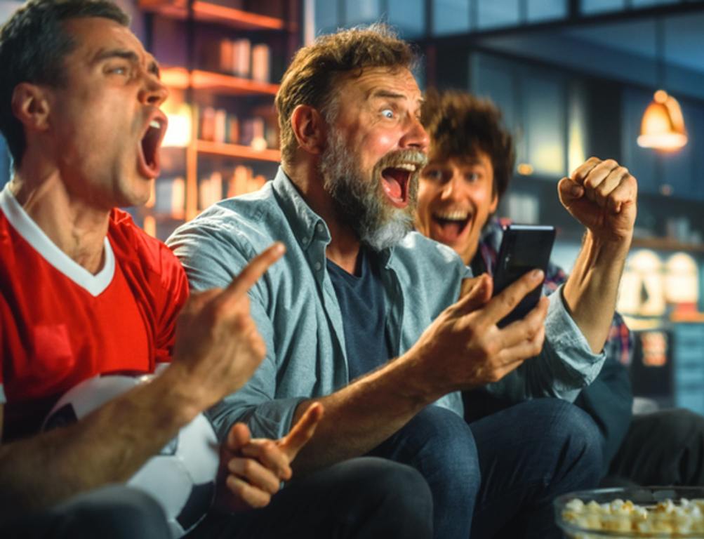 Fans sitting on the couch watching sports.