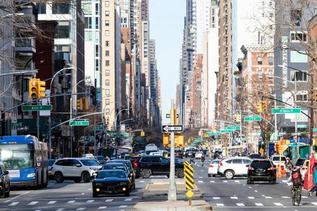 Busy street view with people, cars and buses in the crowded intersections on 3rd Avenue in the East Village neighborhood of New York City NYC