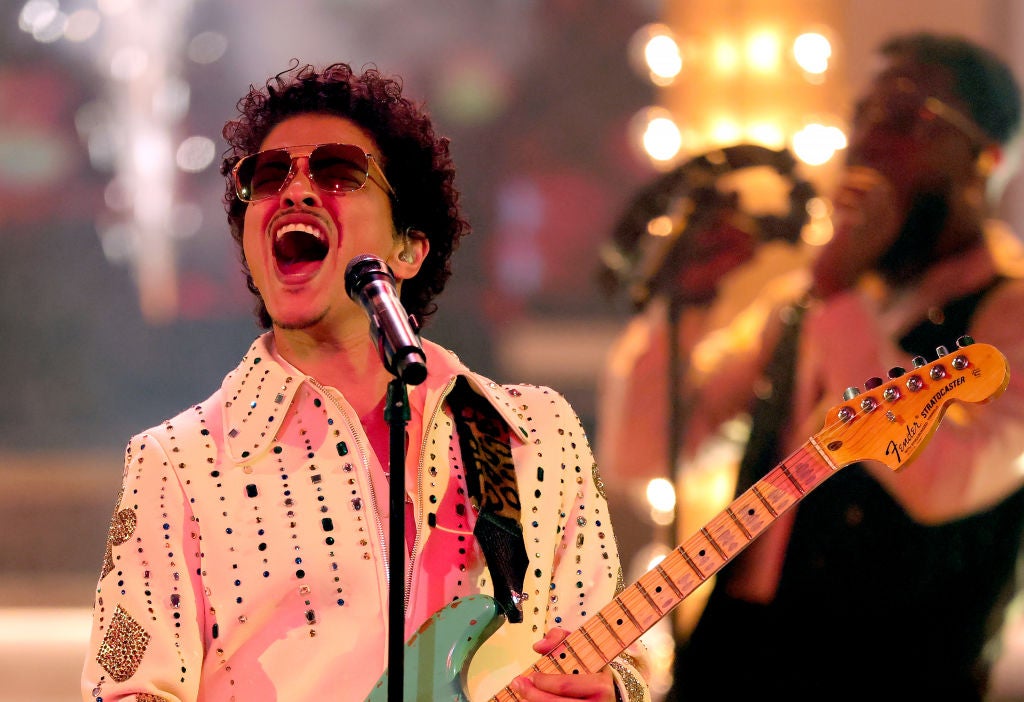 Bruno Mars playing a green Fender Stratocaster guitar