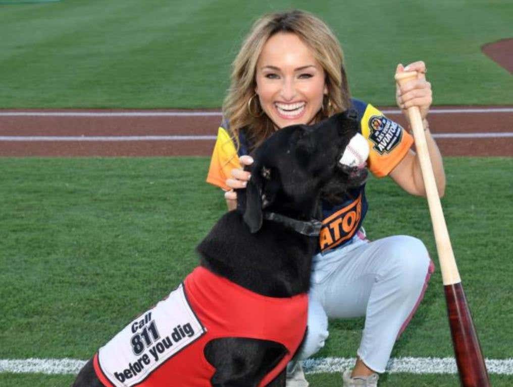 A black lab dog in a red vest with a blonde woman holding a bat. Concept. Finn The Bat dog passes away.