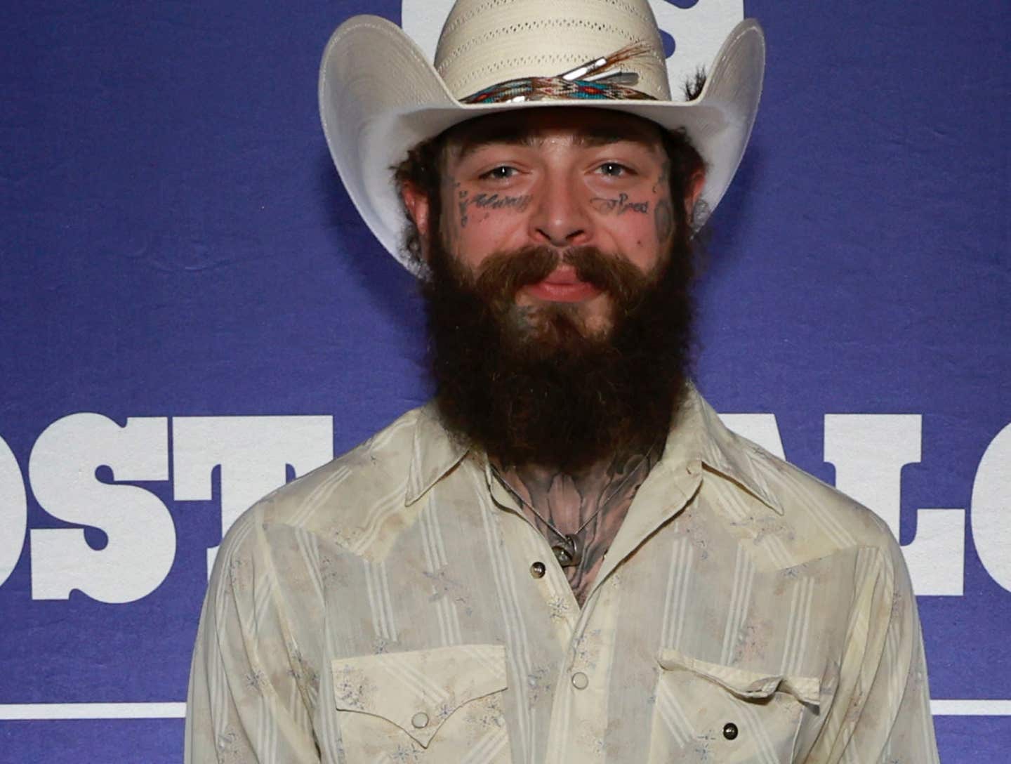 Post Malone posing in a beige cowboy shirt and cowboy hat.